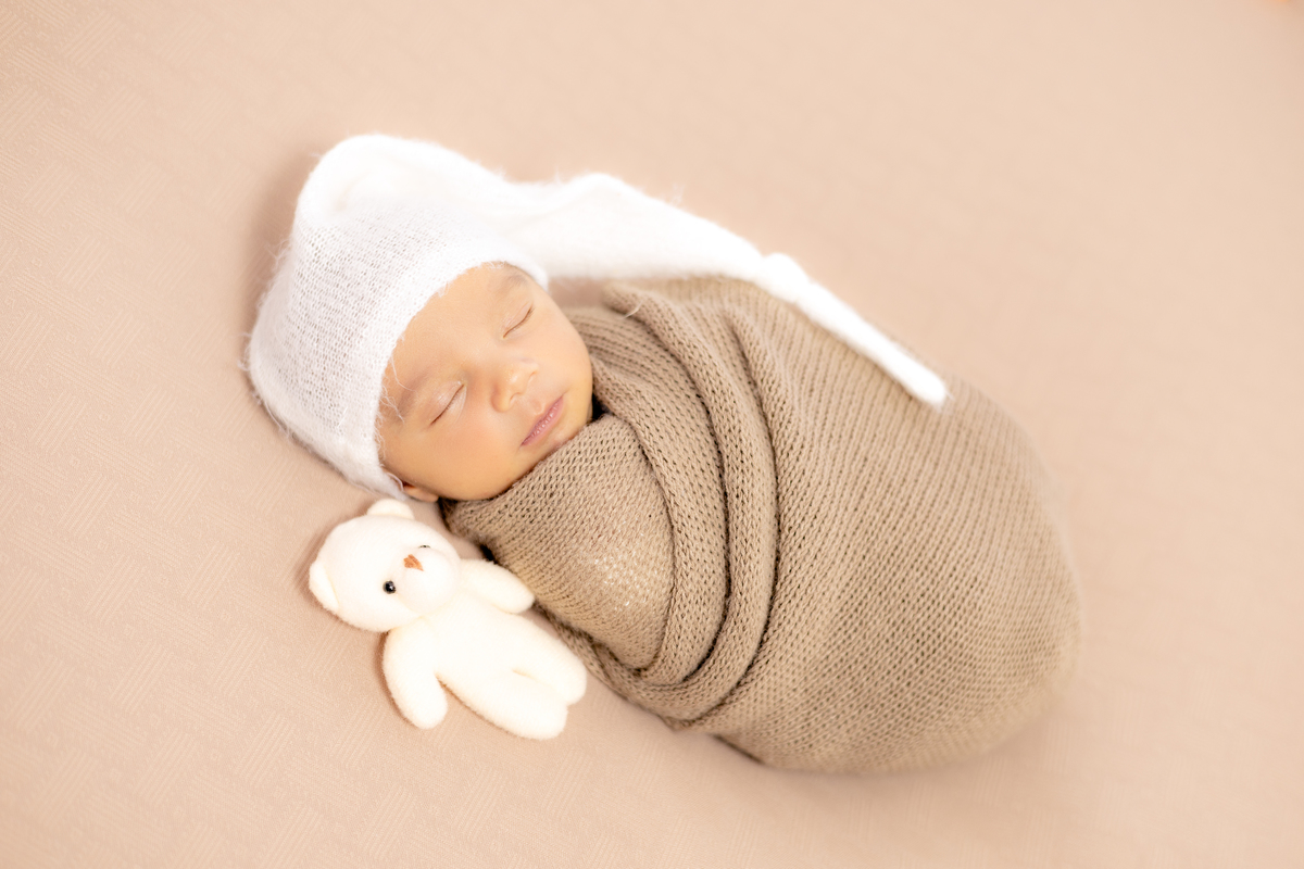 Bebê fofo enrolado no tecido wrap com ursinho