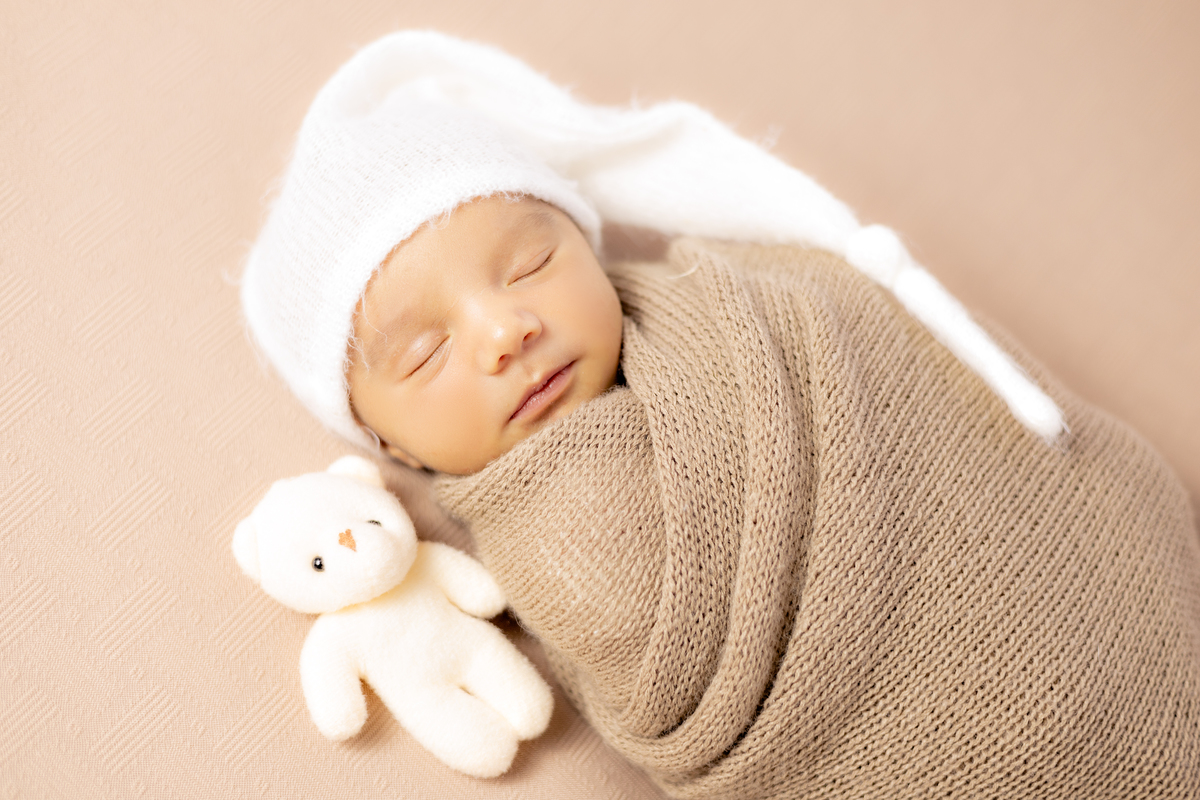 Bebê enrolado no tecido com ursinho 