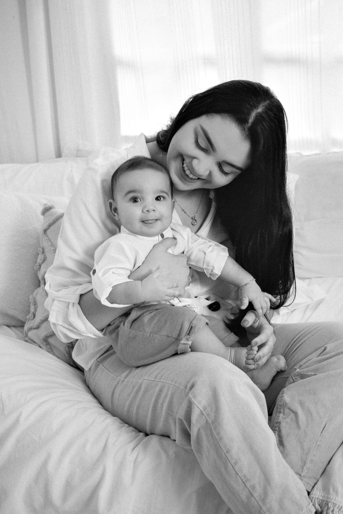 foto mãe sorrindo com o bebê no colo preto e branco