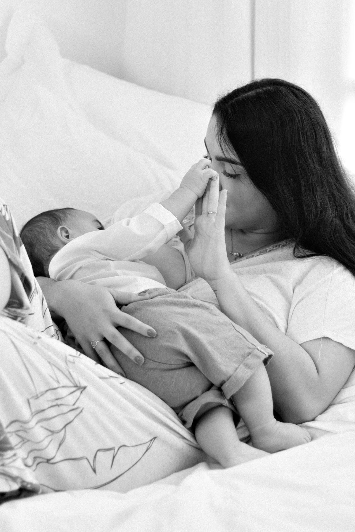 momento fofo da mãe amamentando segurando a mão do bebê