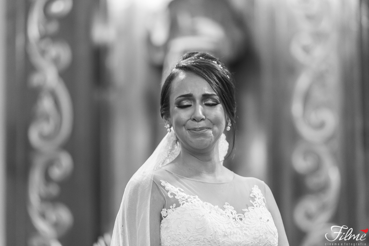 noiva emocionada no altar aguardando a entrada do filho com as alianças