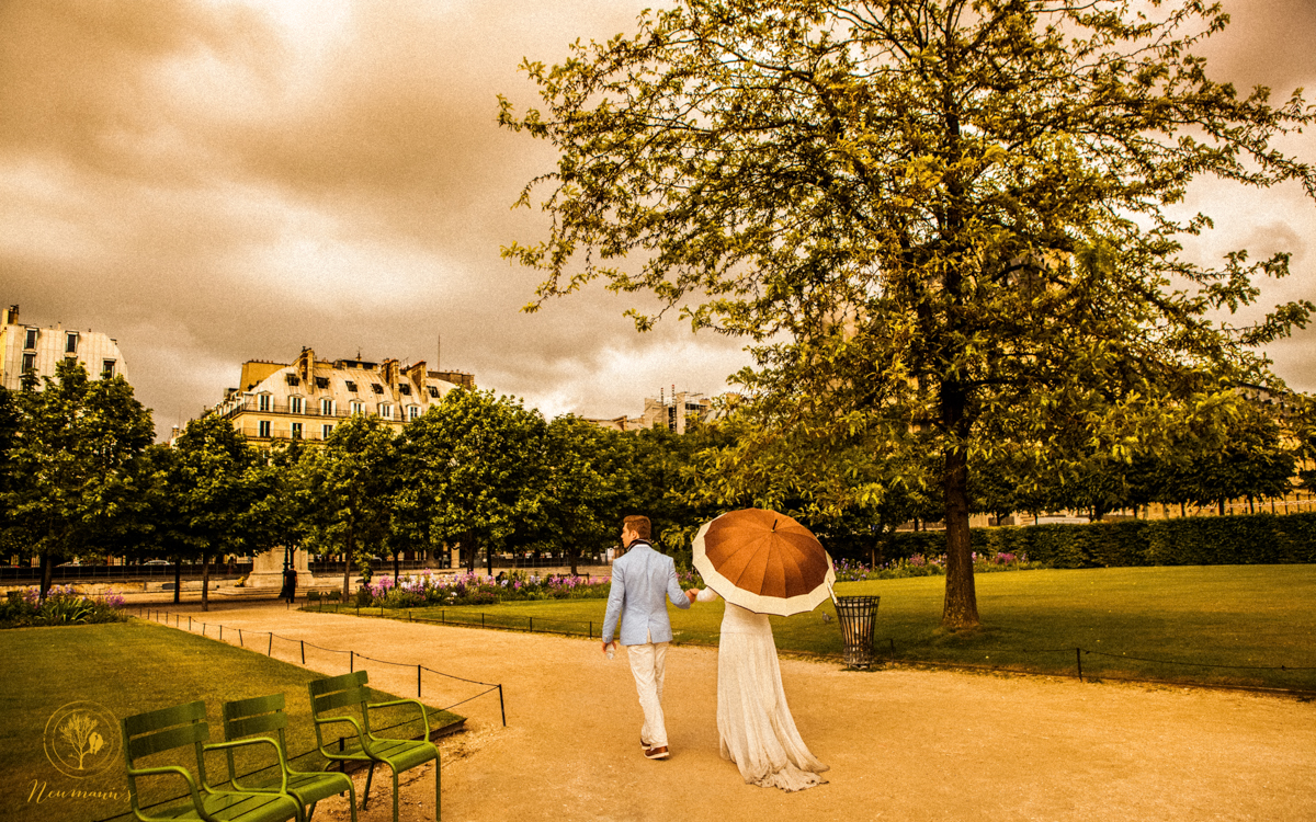 noivos caminhando com guarda chuva no jardim da tulherias no louvre em paris