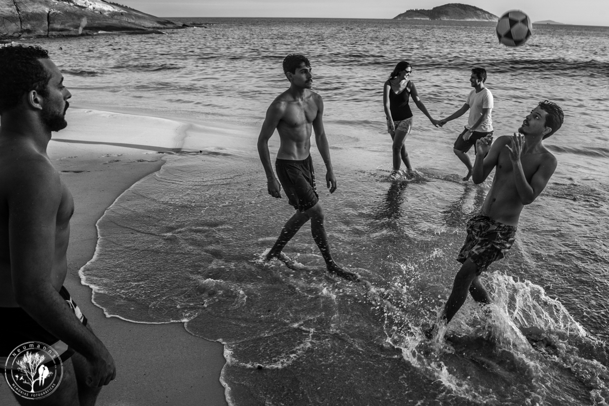sessão pre wedding, casal andando e banhistas brincando de bola na praia do sossego em Niterói, foto neumanns