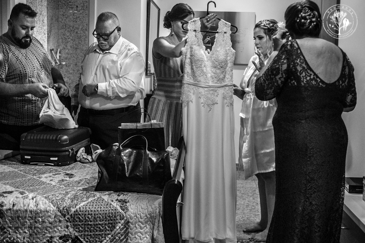 noiva se preparando para colocar o vestido, no quarto junto com seus pais, irmão e prima