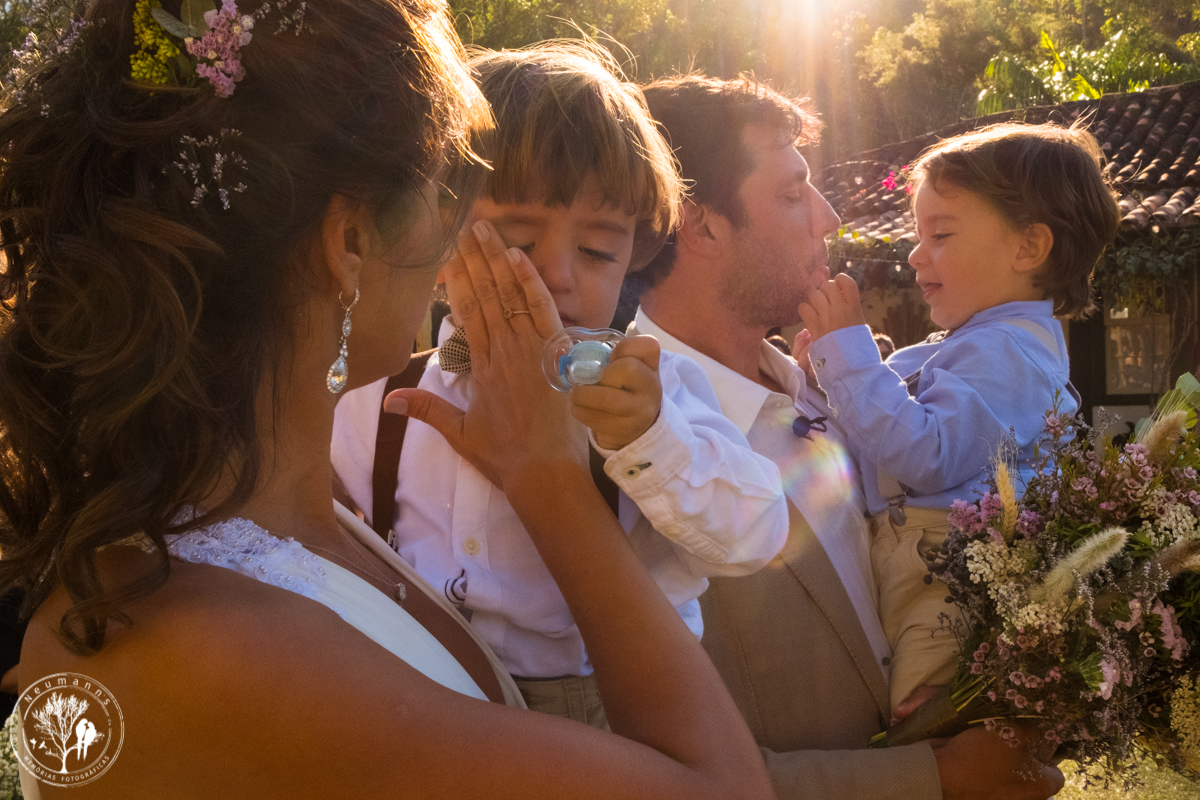 noivos com filhos gêmeos no colo durante a cerimonia de casamento no hotel fazenda união, mãe secando as lágrimas de um, casamento na fazenda união, casamento no campo, casamento na serra, fotos do casamento, neumanns fotografia, cerimonial Vivian Lahr