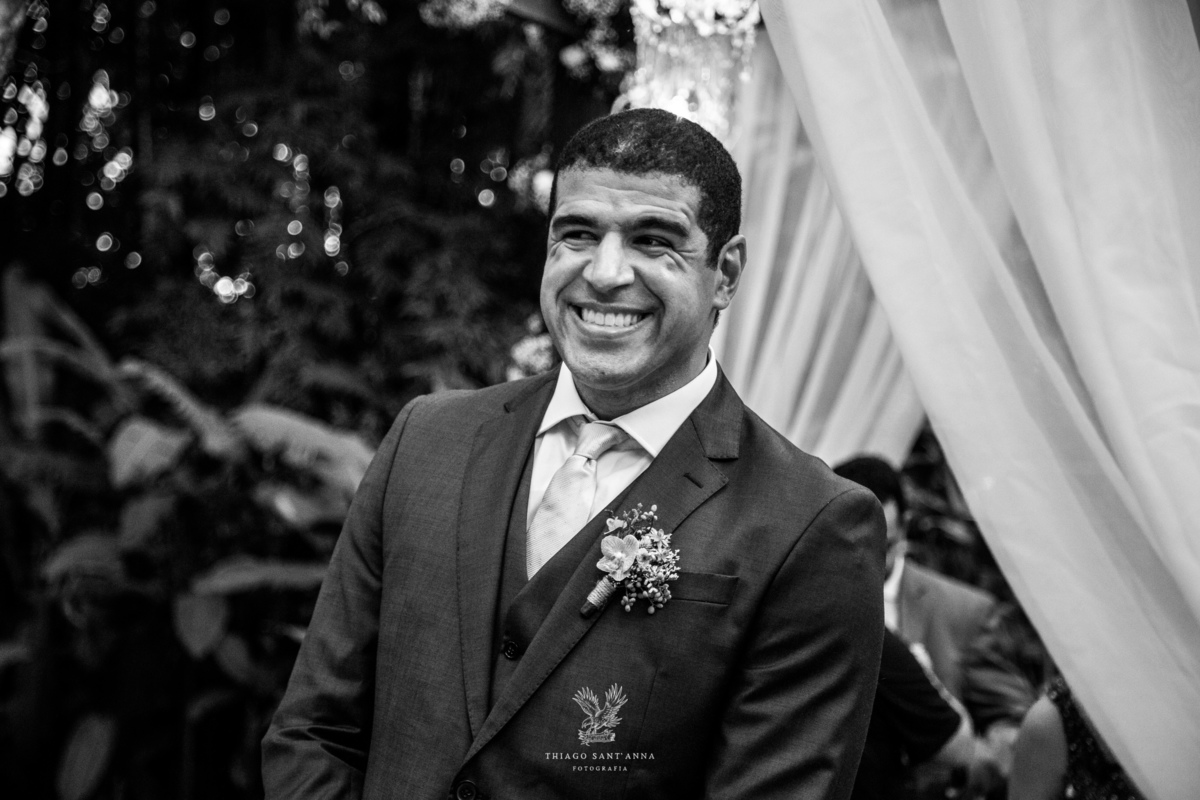 Noivo sorri observando a chegada do pajem preto e branco