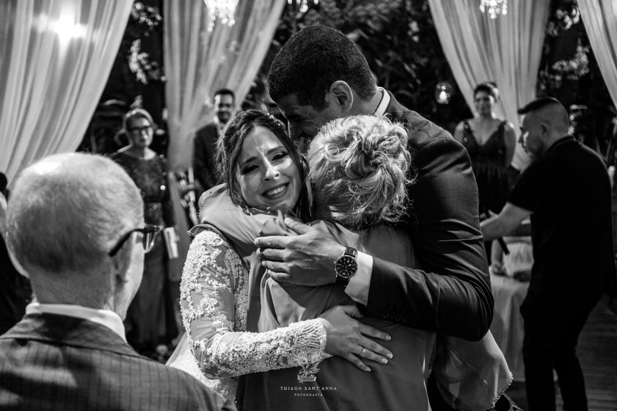 noivos abraçam idosos no altar preto e branco