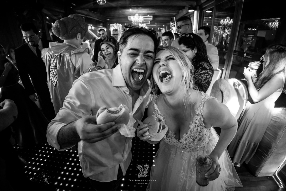 Noivos felizes comem hambúrguer preto e branco 