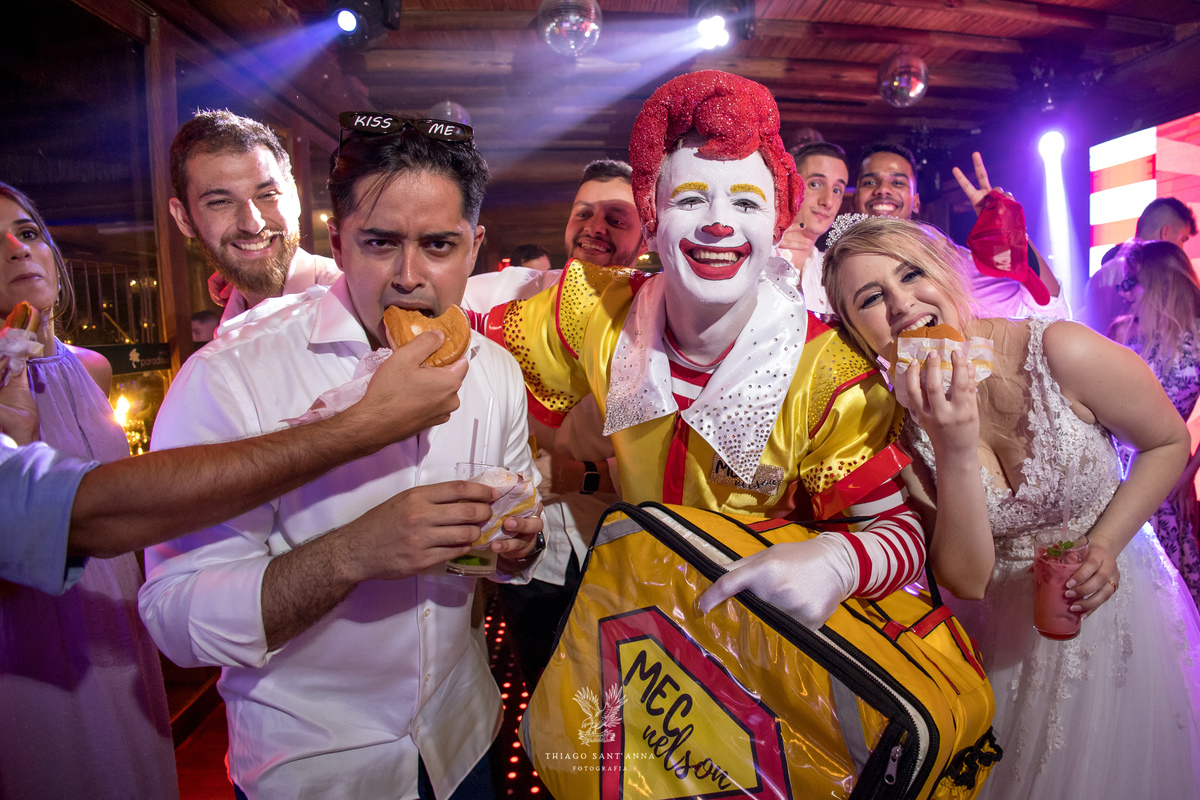 Noivos posam comendo hambúrguer com MC Nelson pista de dança