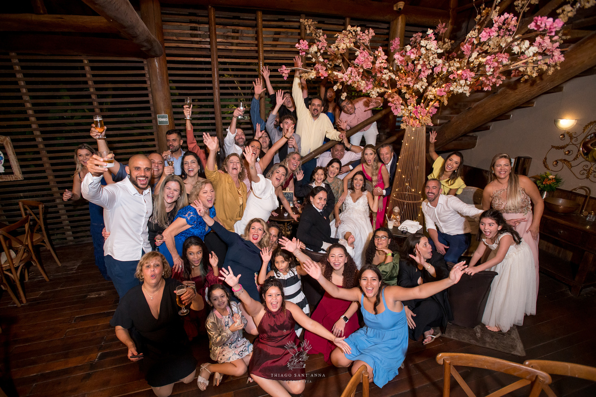 Noivos padrinhos e convidados posam juntos alegres