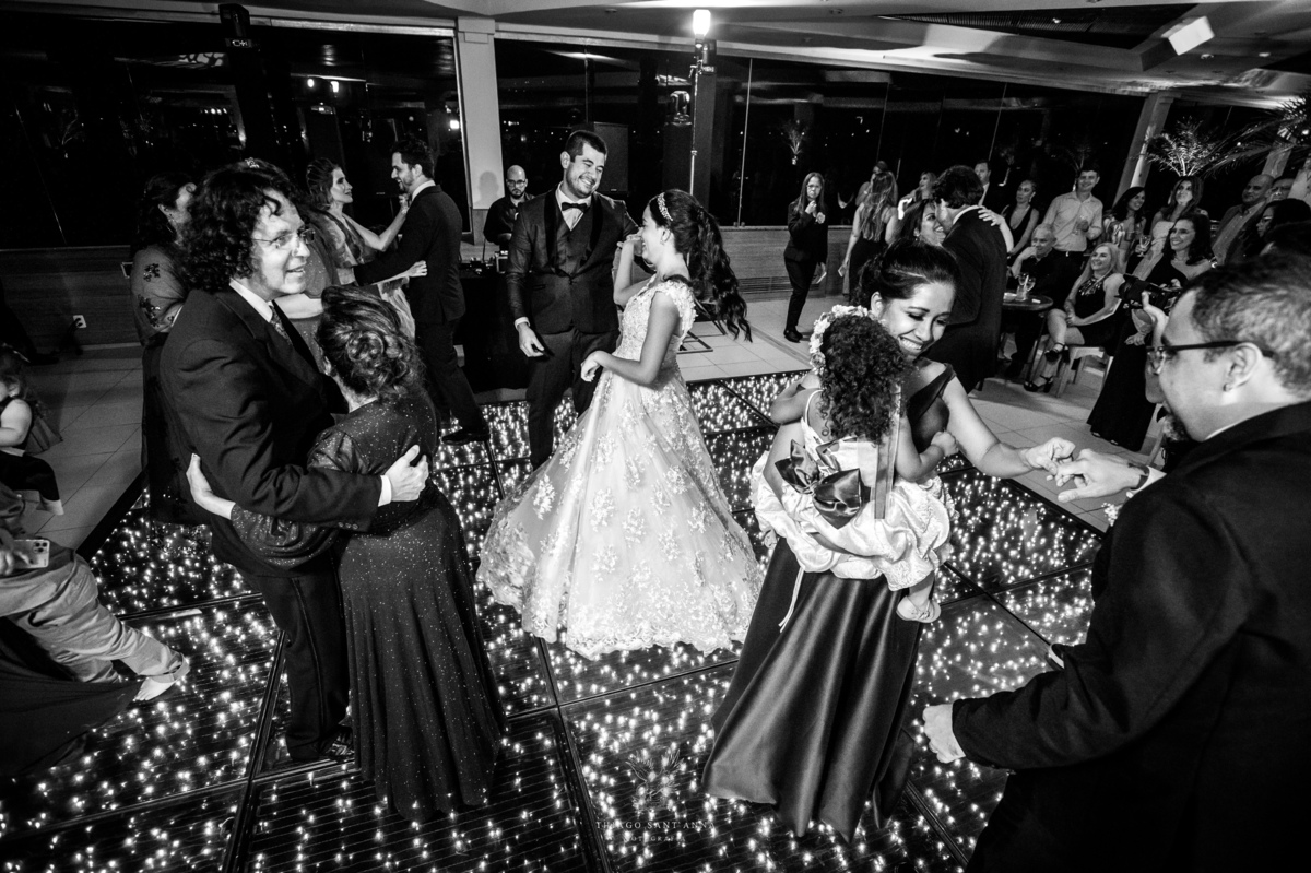 Noivos dançam na pista com madrinhas padrinhos e convidados preto e branco