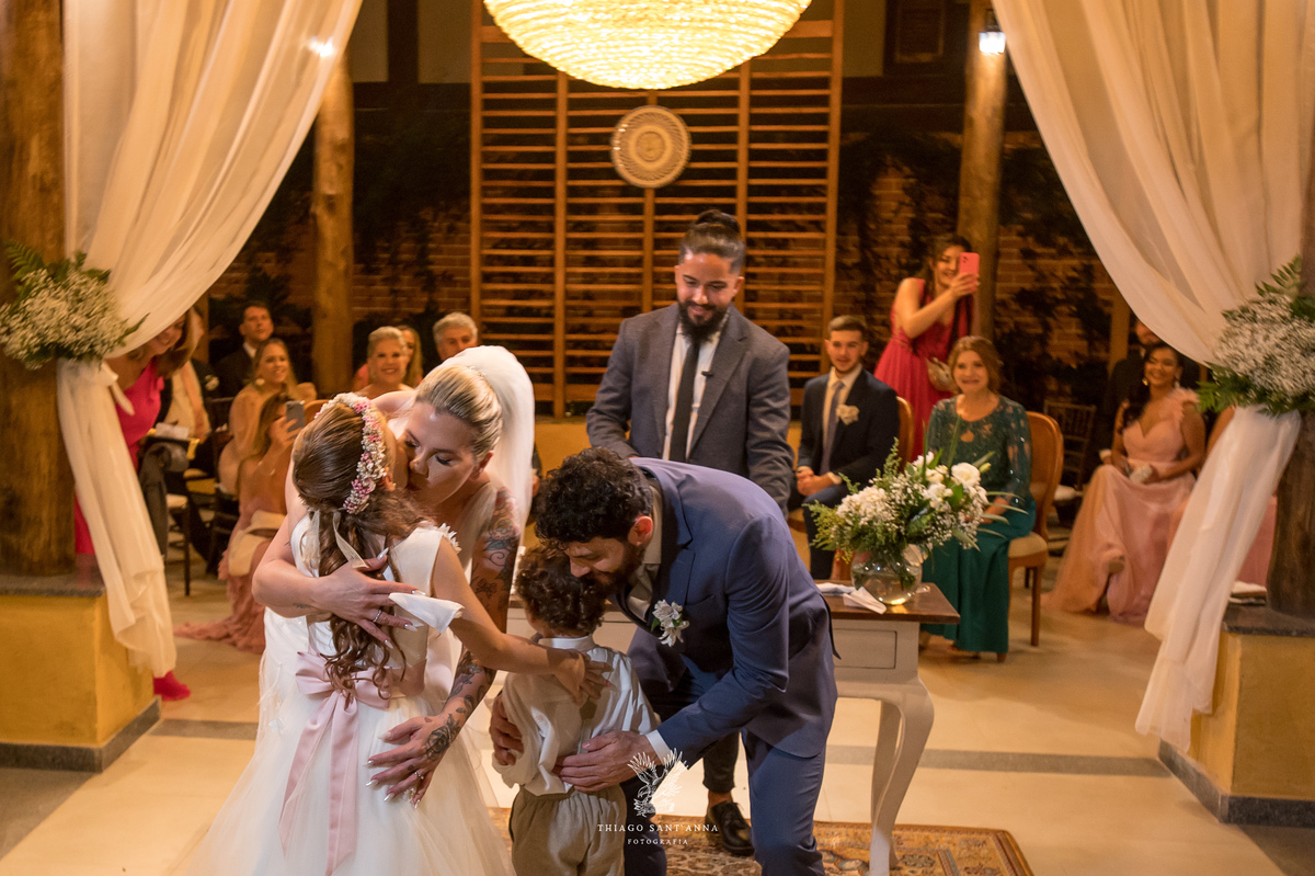 Noivos recebendo a daminha e pagem na cerimônia casamento.