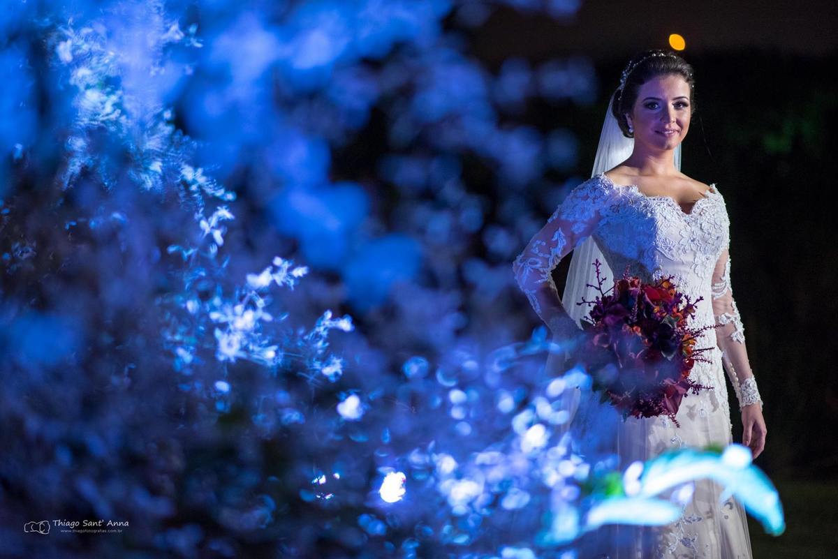 noiva sorri vestido renda buque flores coloridas vegetação ao fundo luz azul