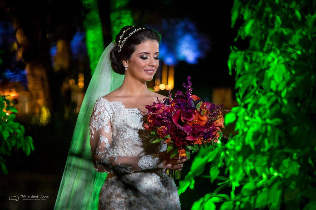 noiva sorri vestido renda buque flores coloridas vegetação ao fundo luz verde