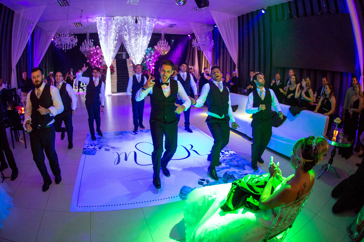 dança do noivo com padrinhos noiva observa sentada