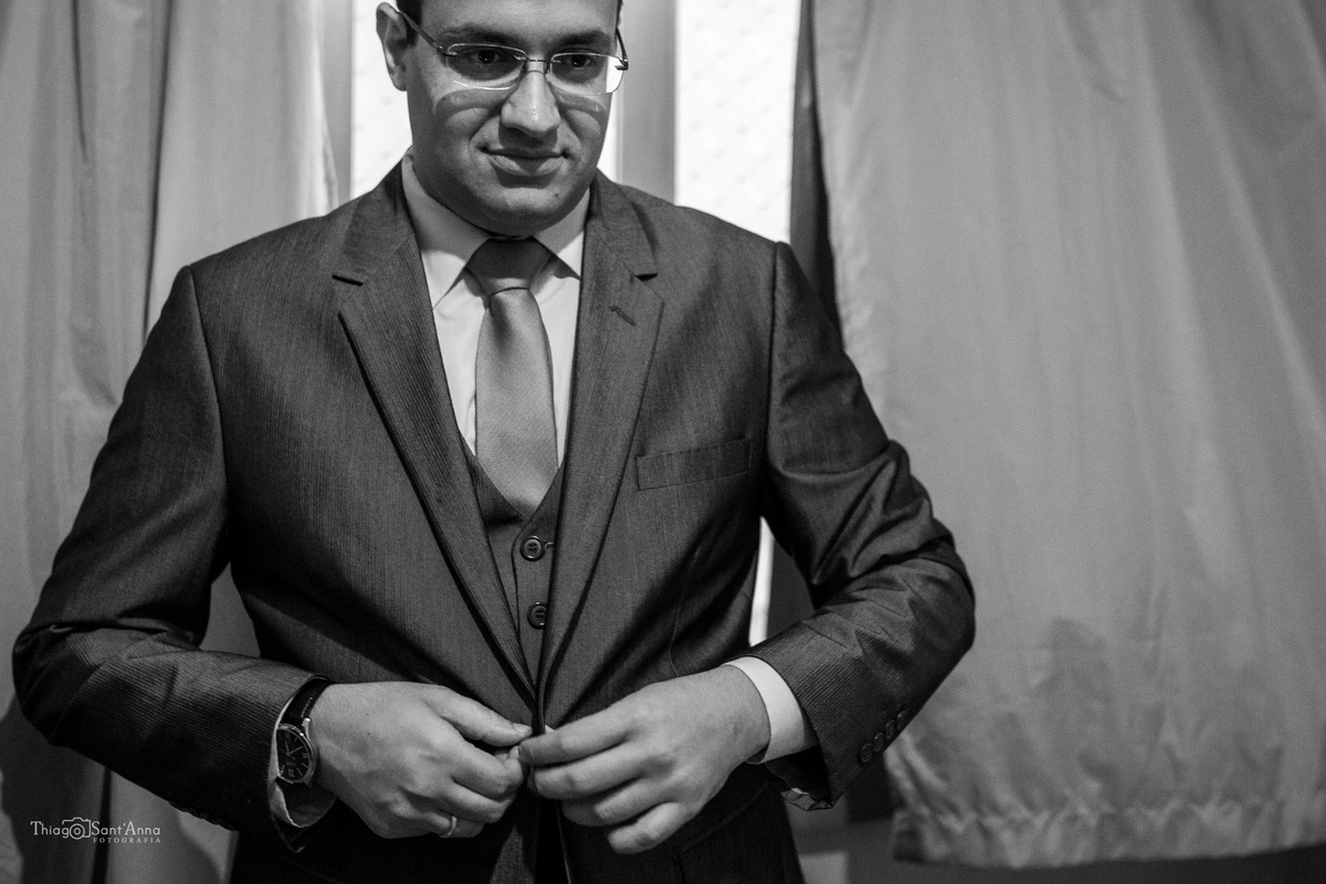 noivo se prepara cerimônia abotoa terno preto e branco