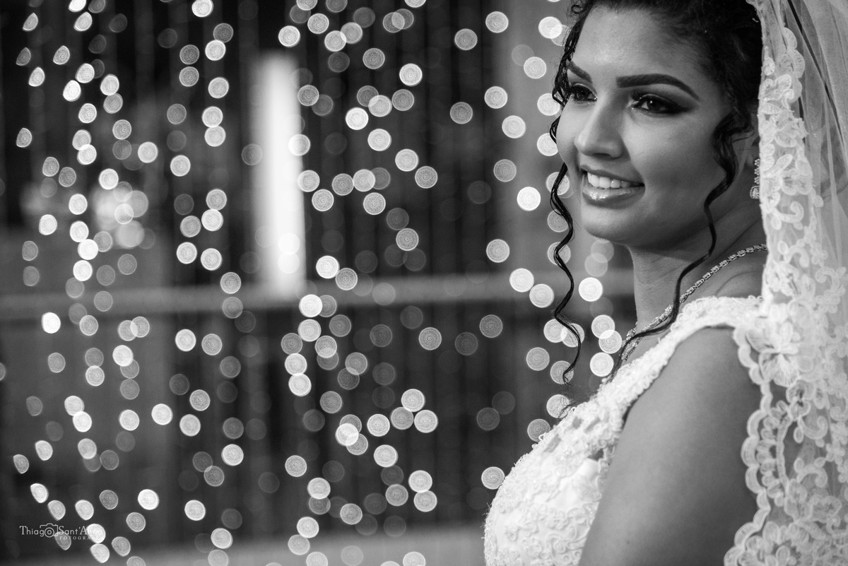 noiva sorri véu renda luzes ao fundo