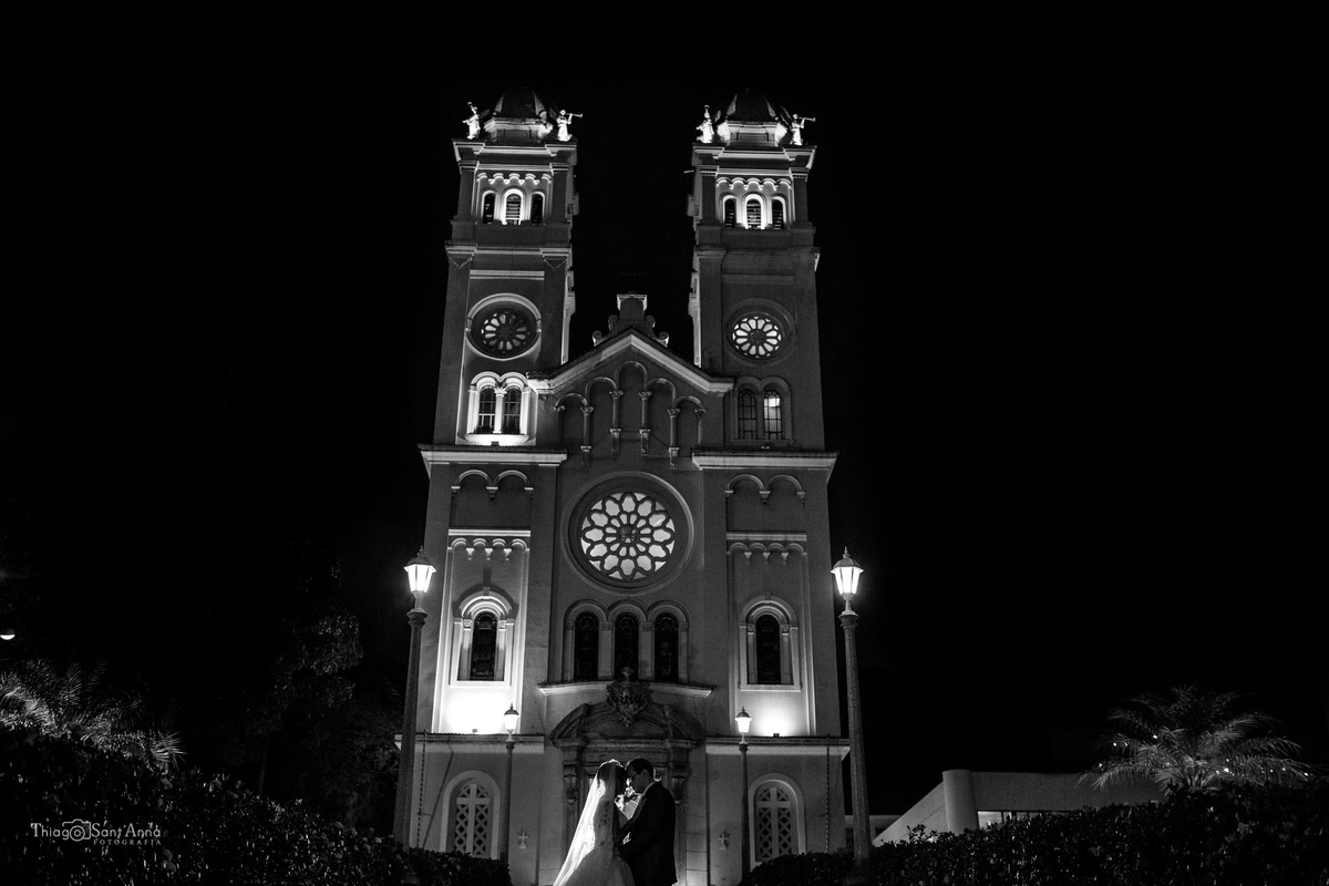 noivos posam frente a igreja preto e branco