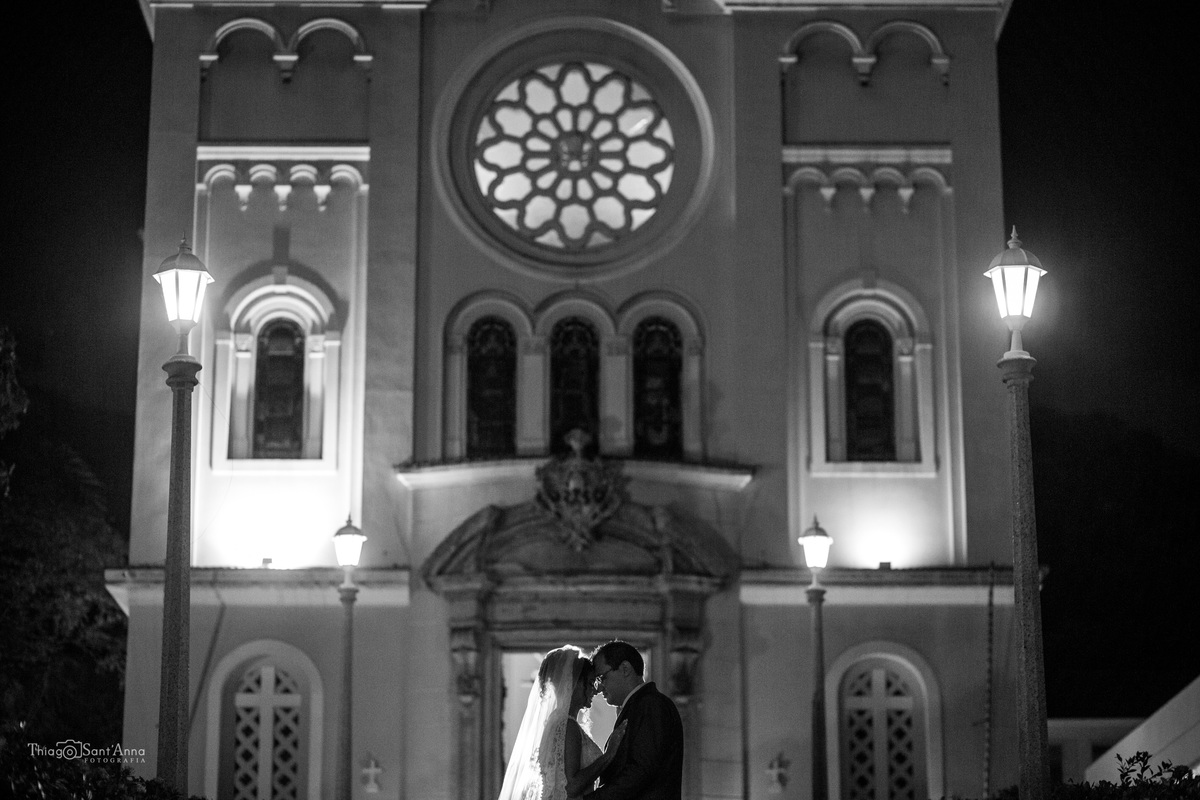 noivos posam frente a igreja preto e branco