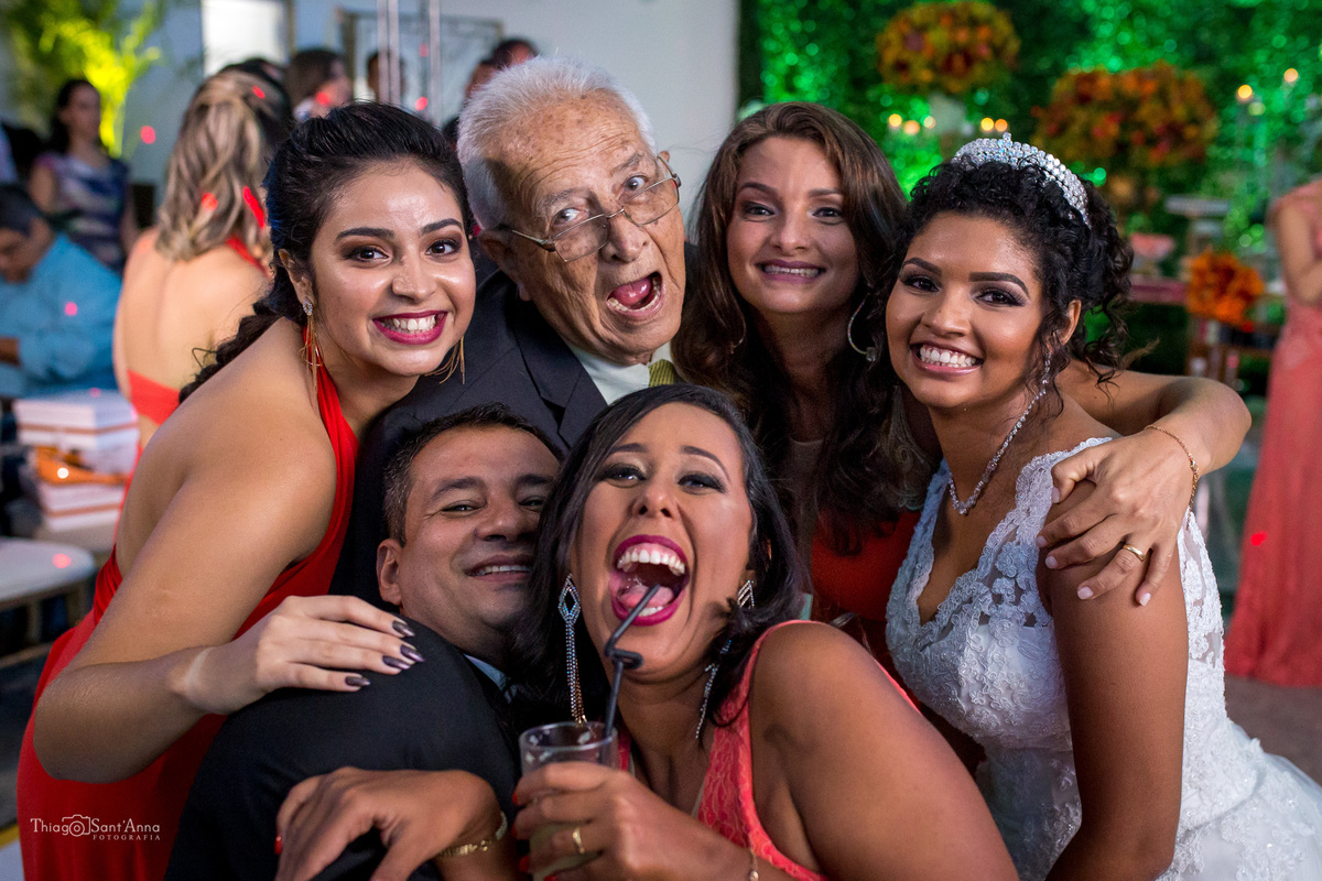 noiva posa sorrindo com madrinhas e convidados