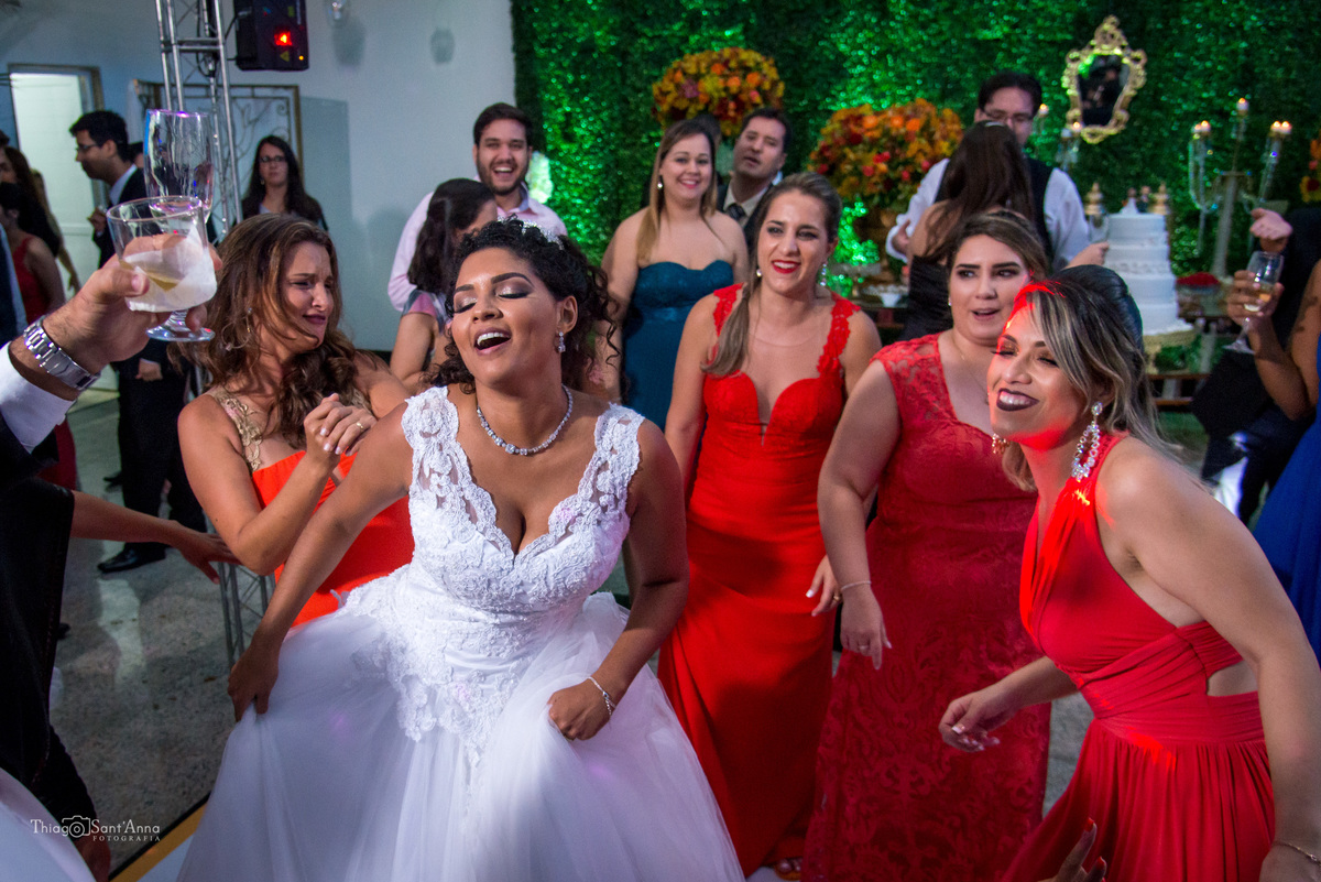 noiva dança sorrindo com madrinhas convidados ao fundo