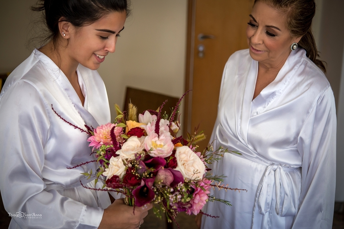 mãe da noiva e noiva admirando o buquê