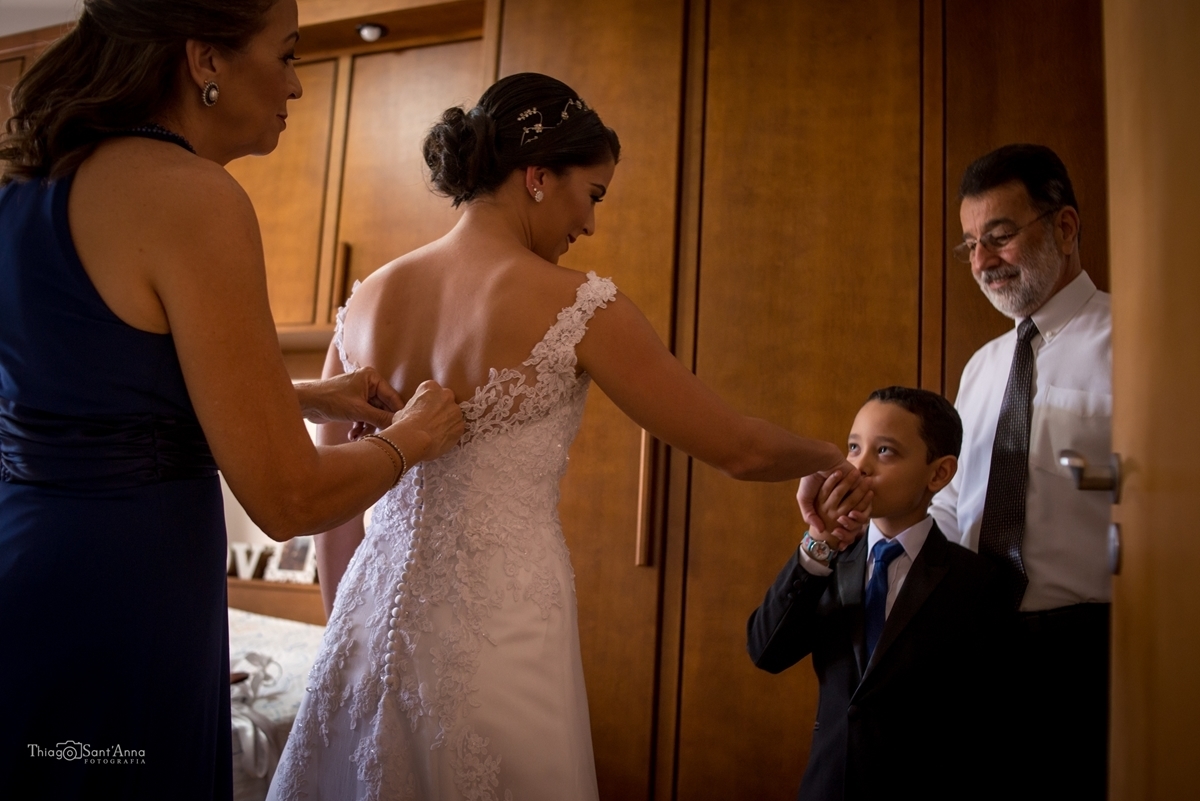 noiva fechando o vestido na companhia da família no making off