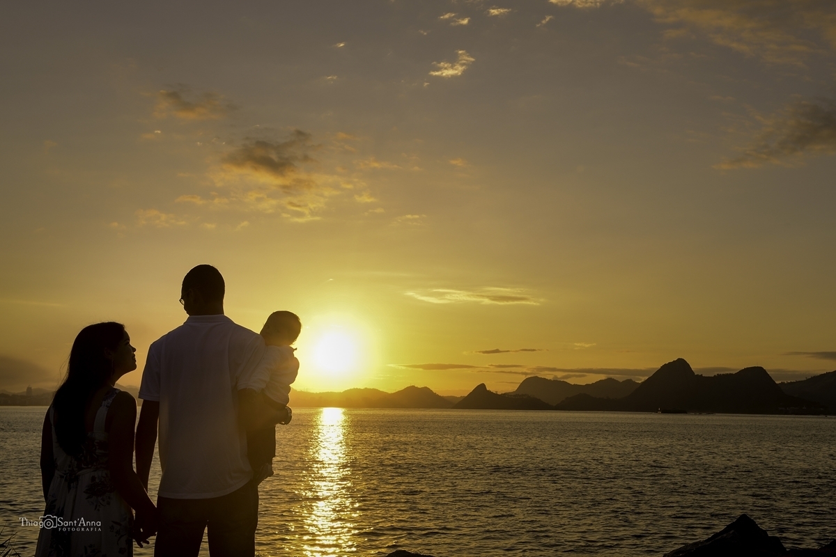casal com seu bebê vendo o horizonte do amanhecer