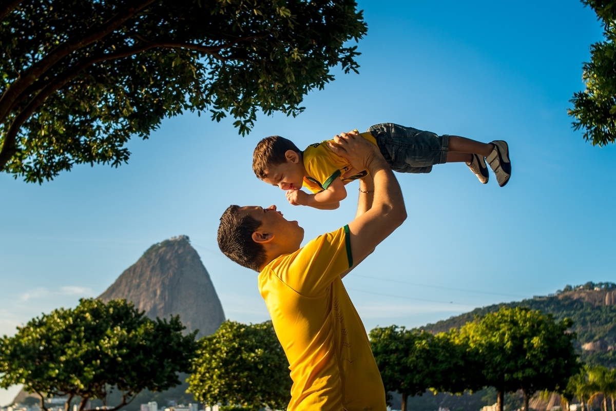 Pai brinca com seu filho com a camisa verde amarela