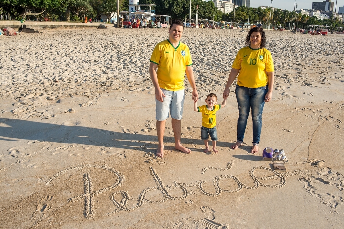 Pai, mãe e filho com escrita na areia