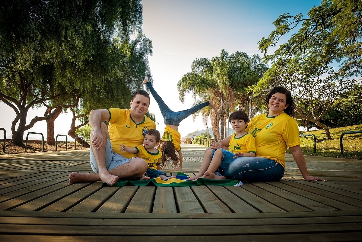 Família Brasileira sentada no deck do aterro do flamengo com a filha dando estrelinha ao fundo