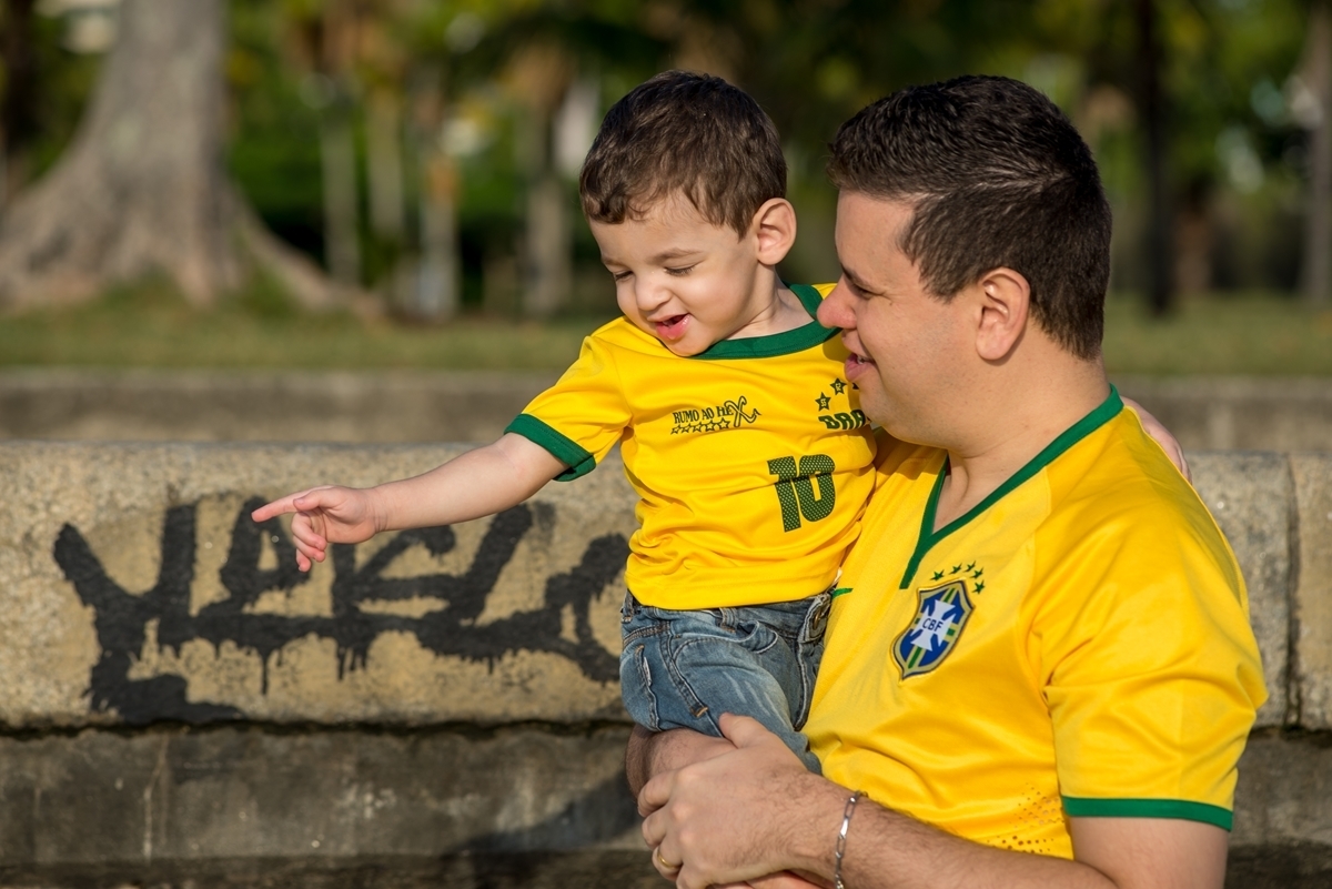 Pai e filho com camisa verde amarela conversando e observando