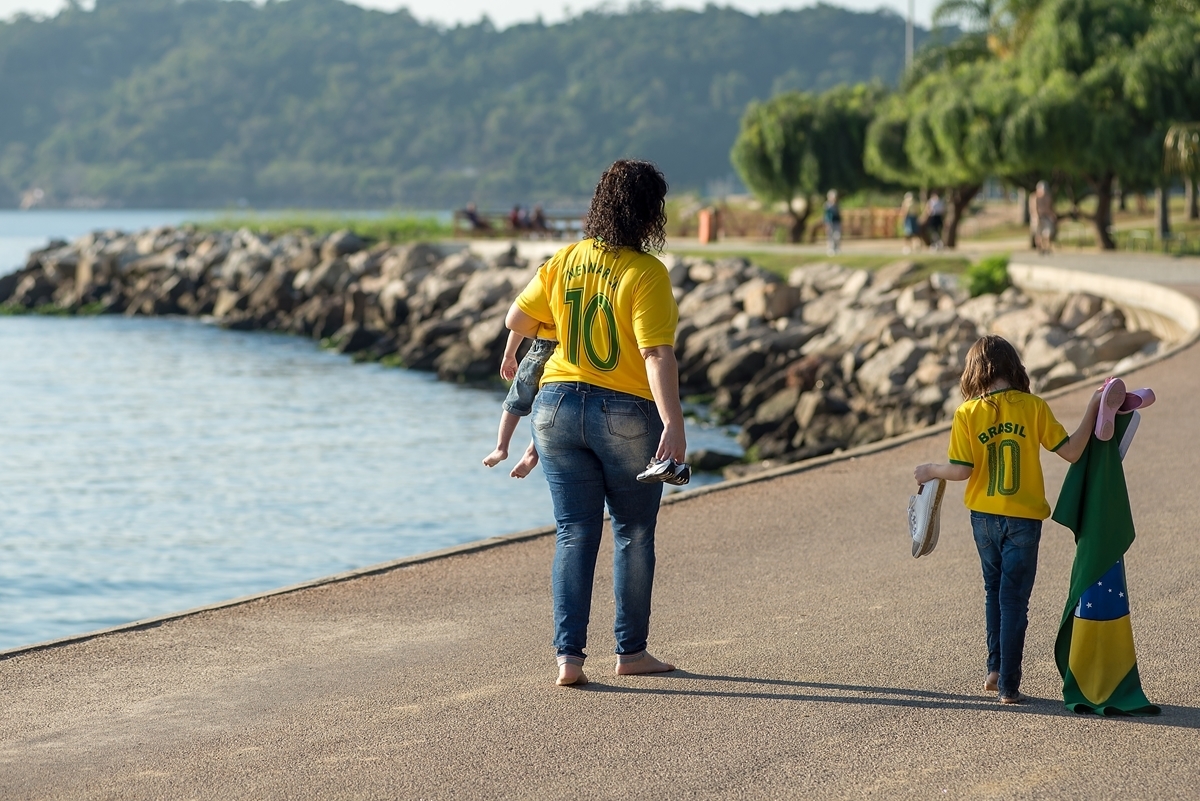 Mãe caminha com seus filhos no aterro do flamengo com a bandeira verde e amarela