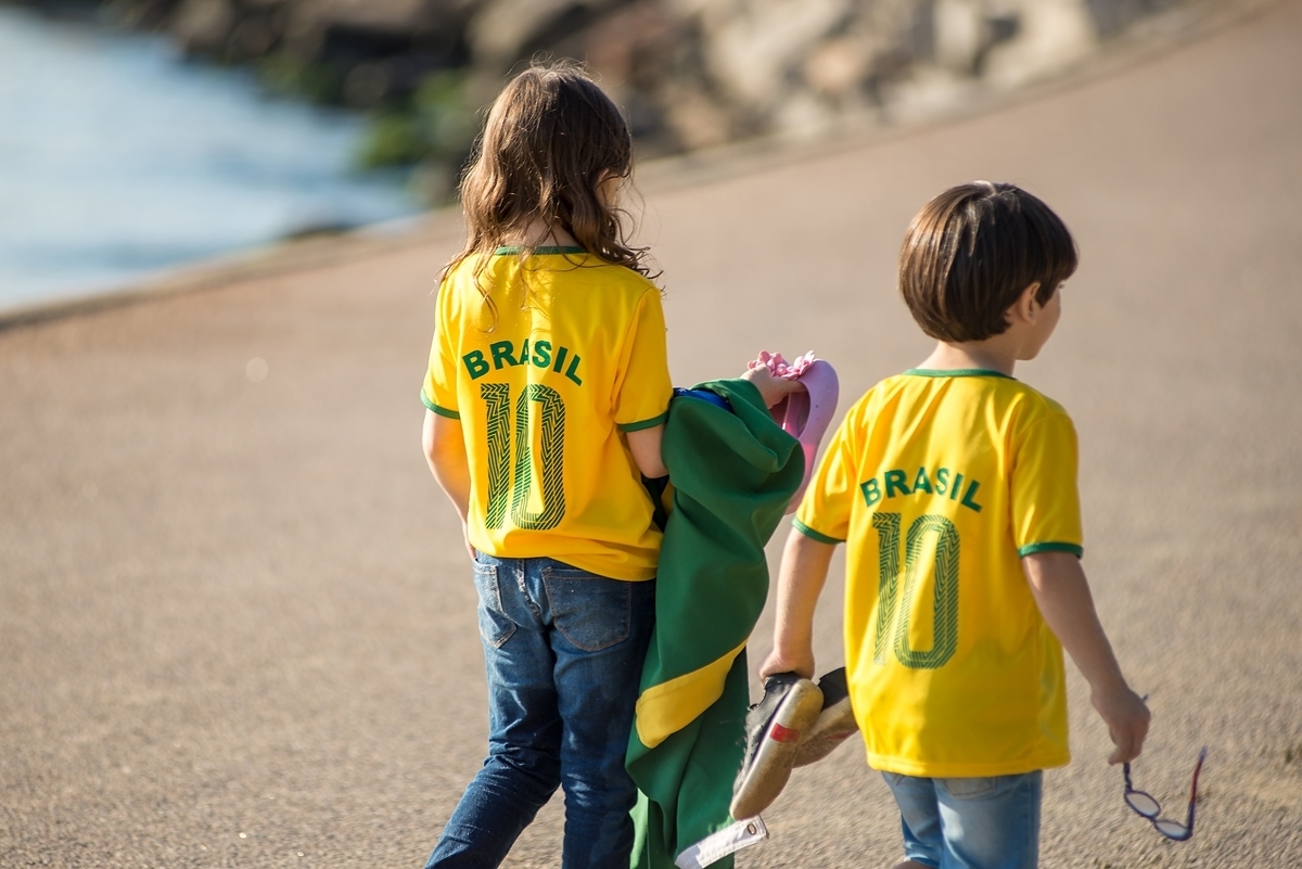 irmãos de costas vestindo a verde e amarela