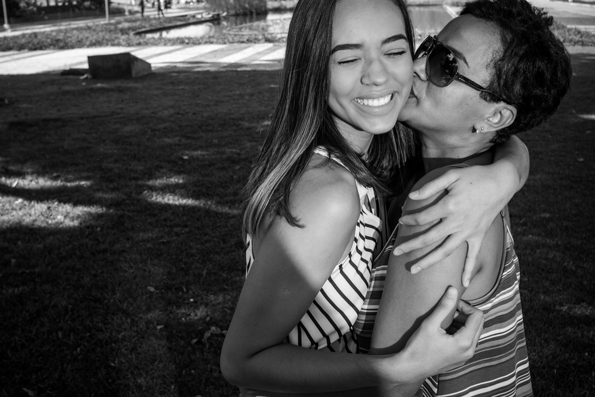 ensaio família mãe beija filha sorri gramado preto e branco