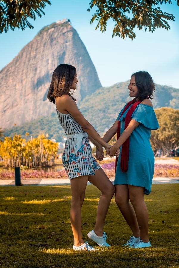 irmãs sorrindo mãos dadas parque montanhas ao fundo