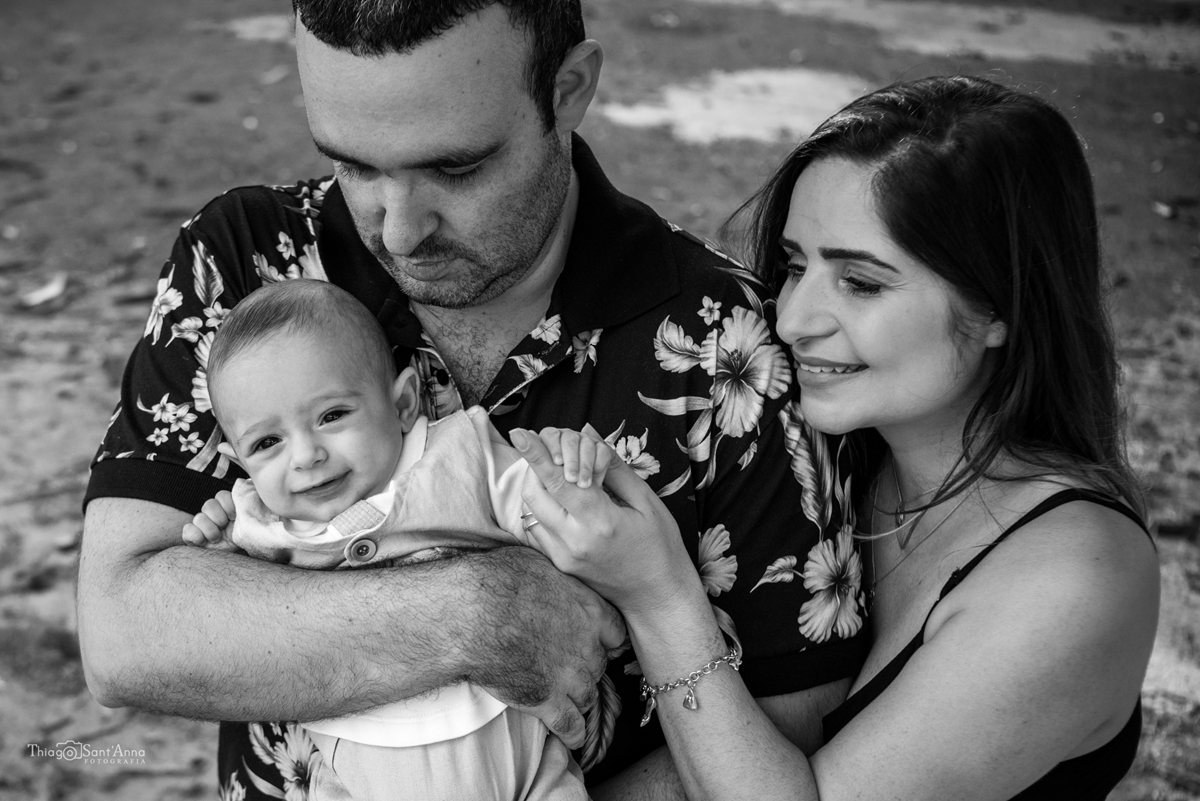 mamãe segurando a mãozinha de seu bebê no colo do papai