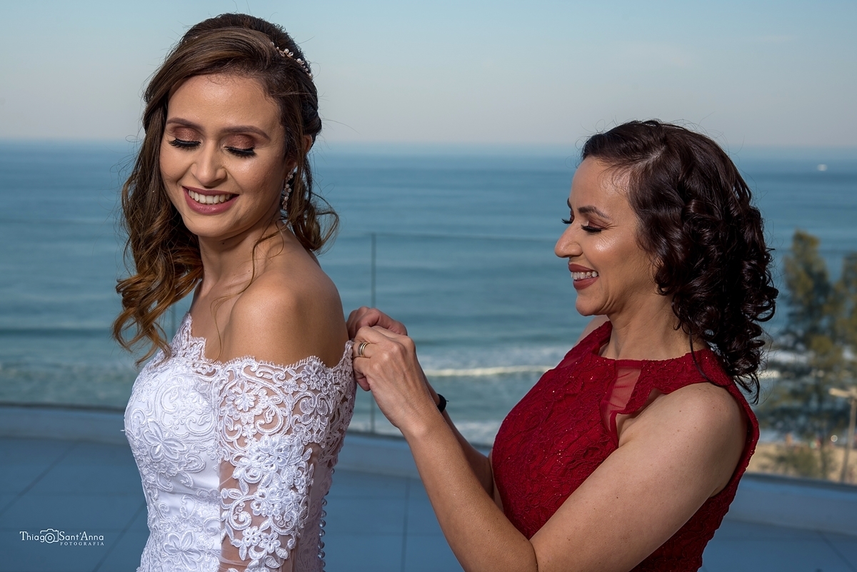 mãe da noiva abotoando o vestido da filha