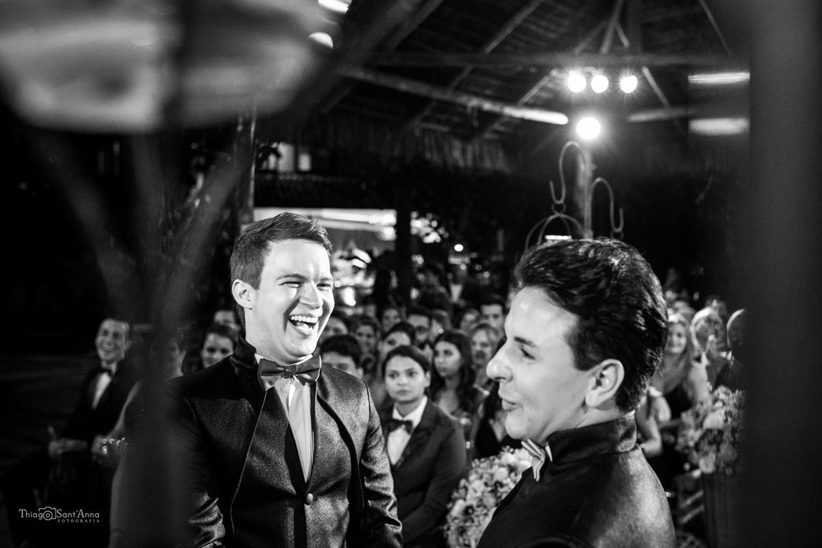 noivos sorrindo no altar convidados ao fundo preto e branco