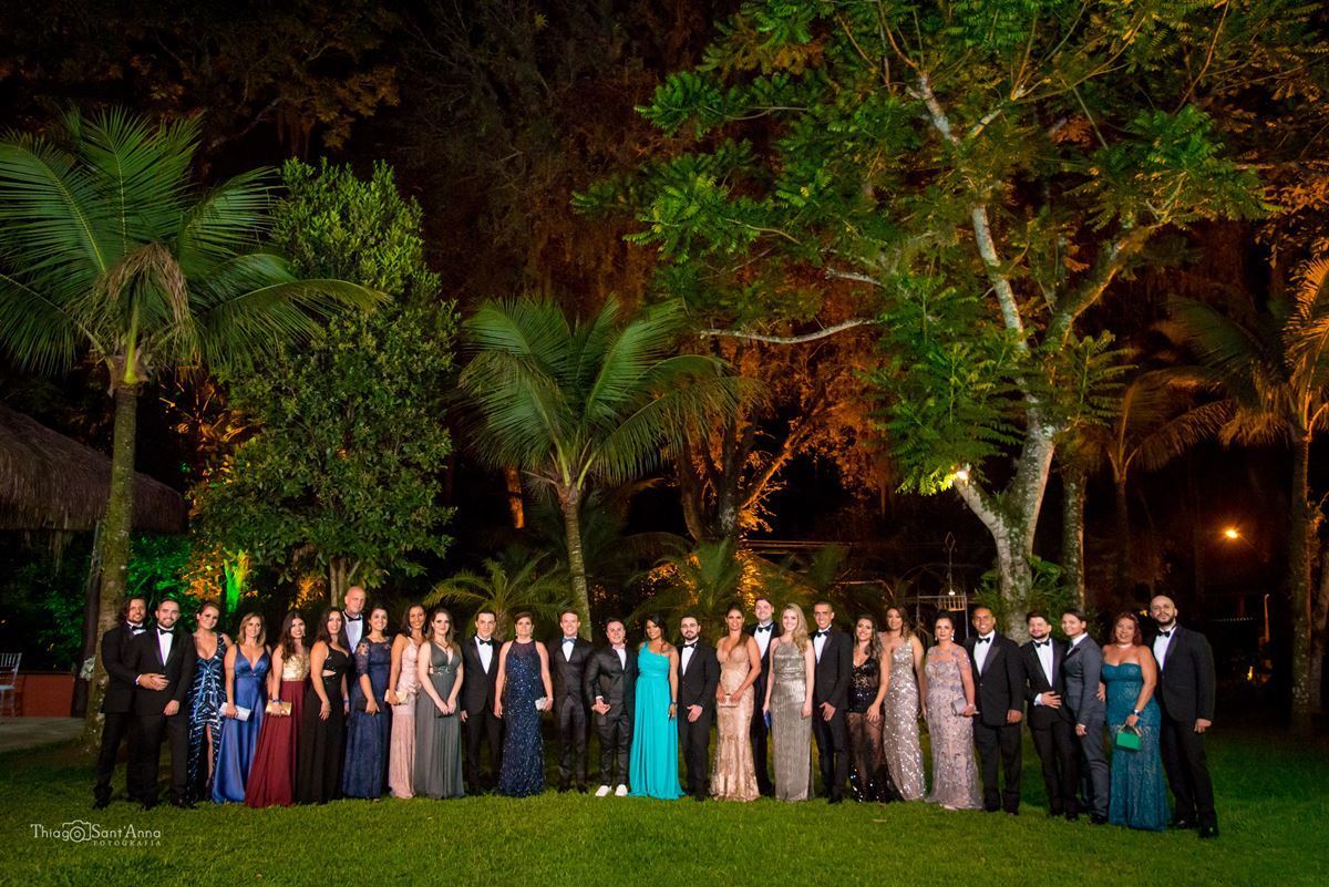 noivos posam com madrinhas e padrinhos ambiente externo vegetação gramado árvores 