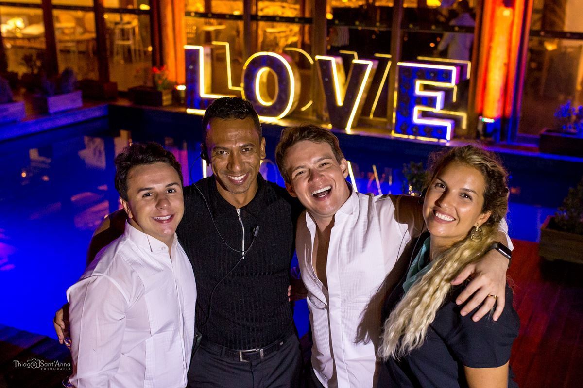 noivos posam com convidados frente a piscina letreiro luminoso