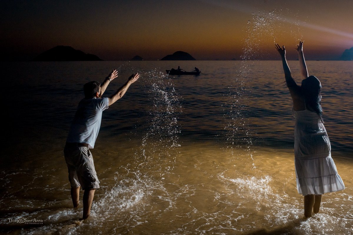 casal se divertindo na água em praia ao anoitecer