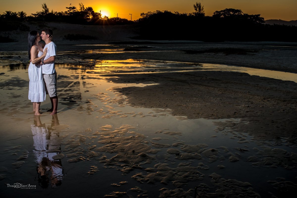 casal namorando na lagoa no contra luz do pôr do sol