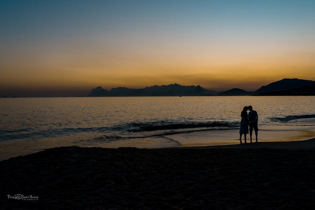 casal namorando na beira da praia a luz do por do sol