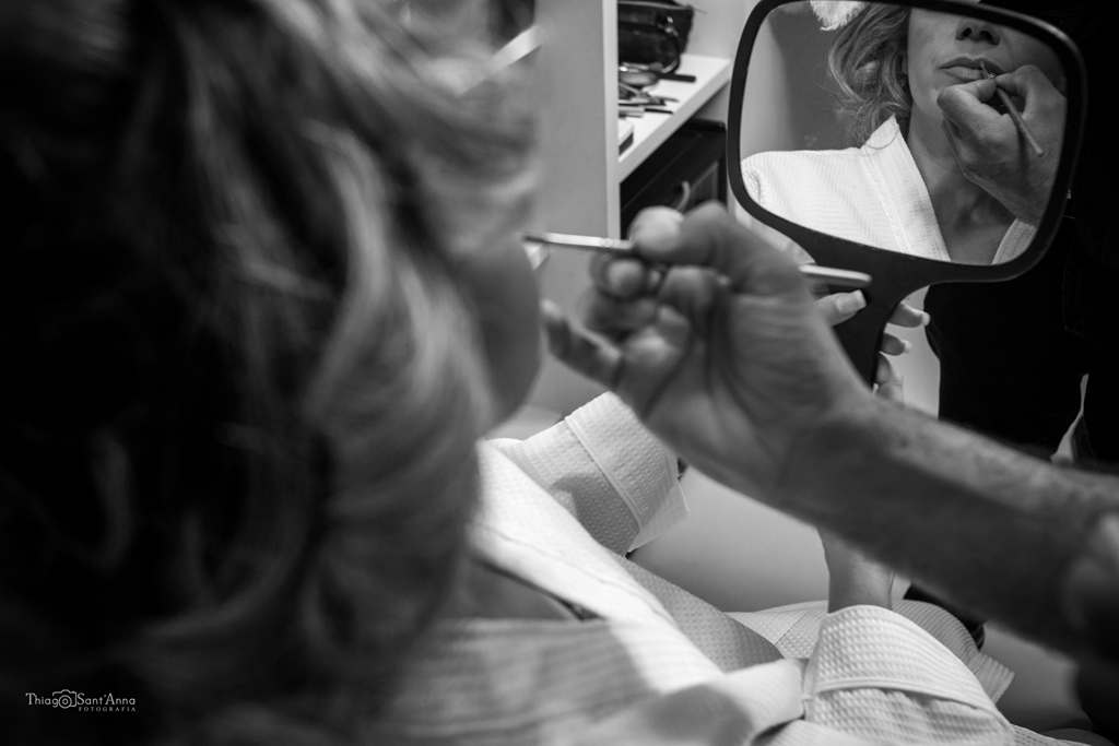 Making off noiva passando batom em frente ao espelho de mão