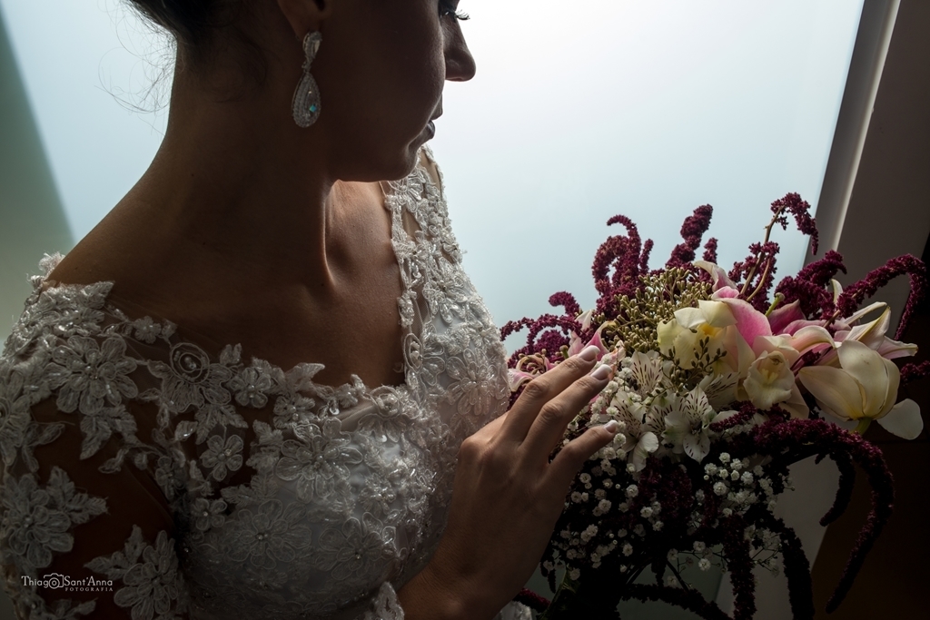 noiva de perfil olhando o buquê com o colo em destaque
