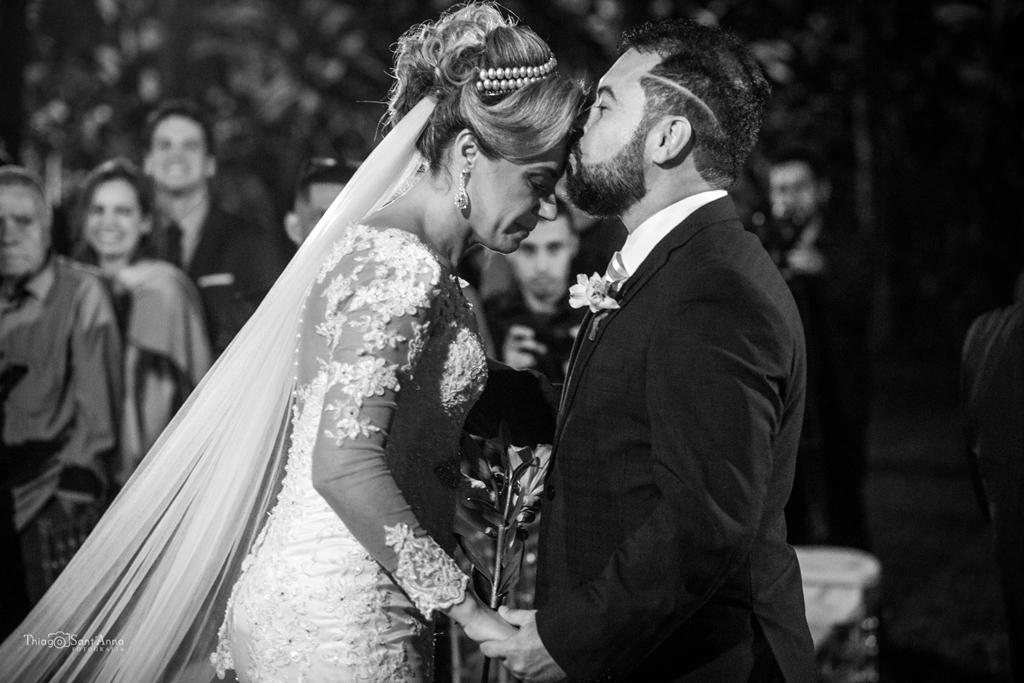 noivo beija sua noiva na testa na cerimônia de casamento em preto e branco