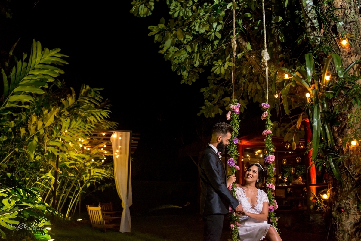 Noivo admira sua noiva sentada no balanço de uma árvore 