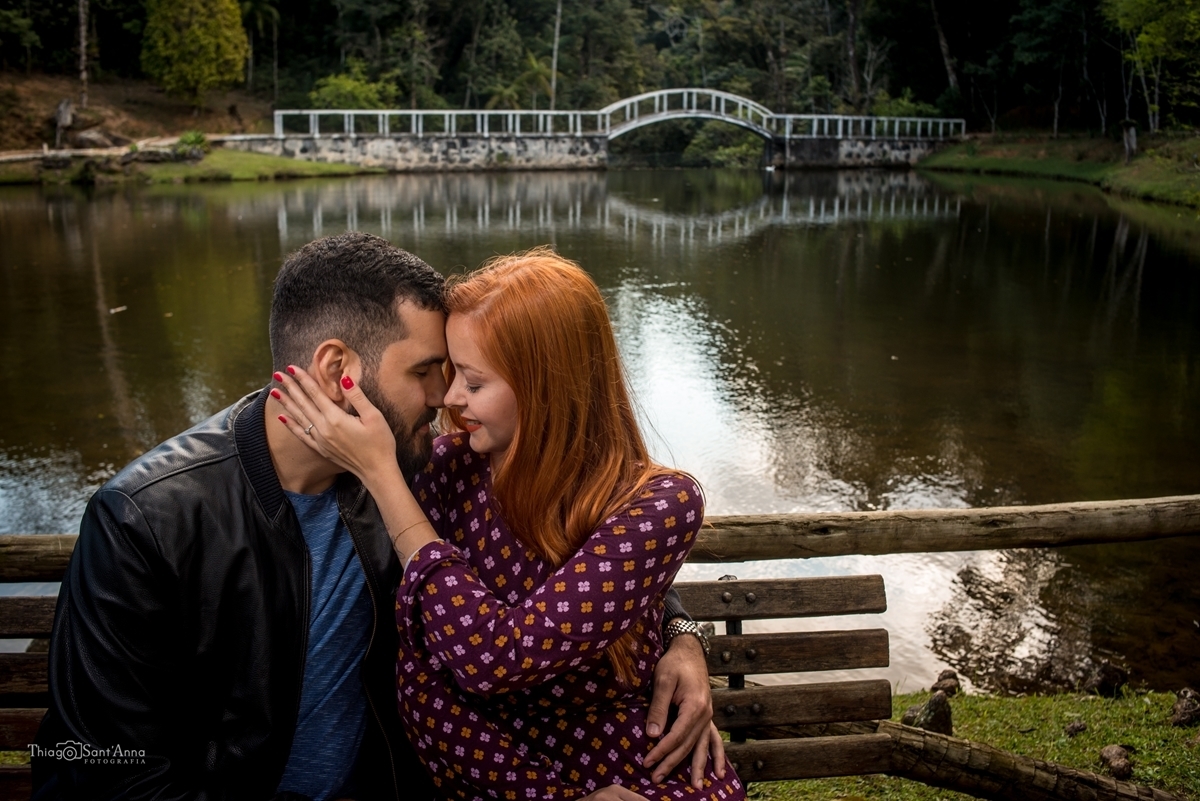 Casal namorando no banco em frente a ponte no lago