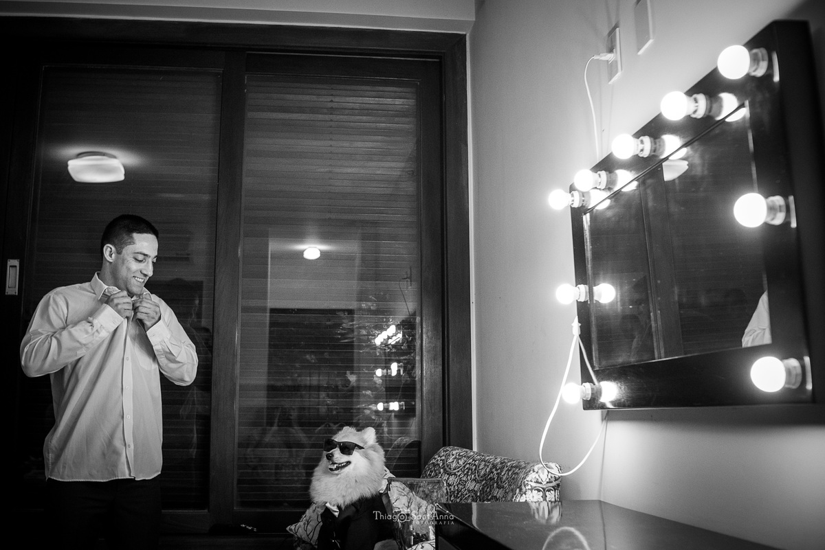 noivo abotoa a camisa observando seu pet preto e branco